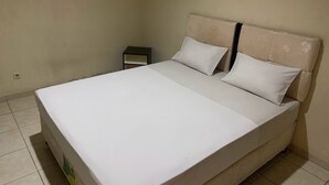 Una cama individual con cabecera, mesita de noche y toma de corriente.