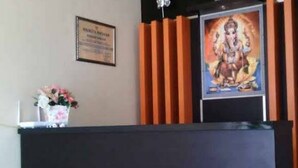 Un mostrador de recepción con un certificado en el marco, un florero y un cartel de una divinidad.