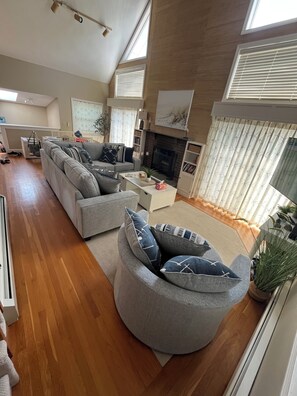 A modern living room with a sectional sofa, a fireplace, and a large window.