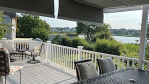 Une terrasse extérieure couverte offrant une vue sur un lac et la végétation environnante.