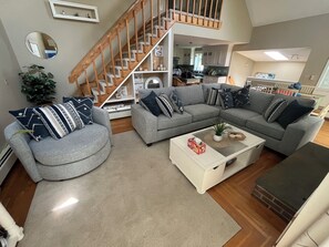 Una sala de estar moderna con un sofá seccional gris, una mesa de centro blanca y una escalera de madera.