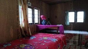 Une pièce en bois avec un lit, un bureau et deux fenêtres.