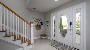 A clean, modern entryway with a white door, a wooden staircase, and a small rug. - DOG FRIENDLY-POOL/TENNIS COMMTY CLOSE TO REHO BEACH & BOARDS -37287 Trent Ct. (Rehoboth Beach)