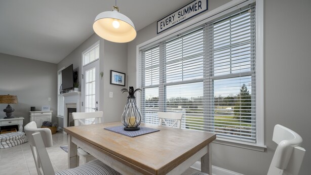A dining area with a wooden table, white chairs, and a hanging light fixture. - DOG FRIENDLY-POOL/TENNIS COMMTY CLOSE TO REHO BEACH & BOARDS -37287 Trent Ct. (Rehoboth Beach)