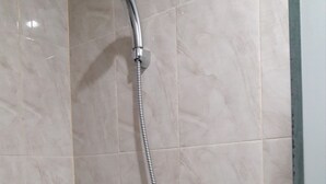Douchekop met flexibele slang voor een betegelde muur.