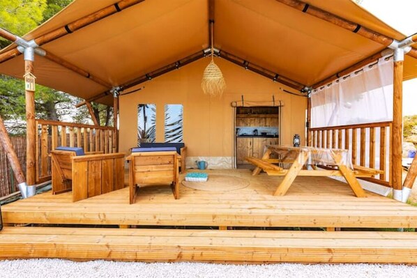 A wooden deck with a covered seating area, a table, and a hanging light fixture.