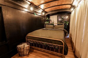 Een compacte, knusse slaapkamer met een eenpersoonsbed, een klein nachtkastje en een rieten mand.