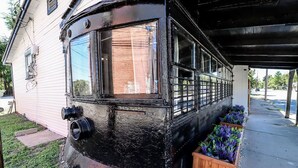 Ein restaurierter Zugwaggon, der als Haus umgebaut wurde, mit einem großen Fenster und einer kleinen Veranda.