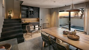 Enjoy meals in this dining area with a long table for two, wicker chairs, and a wine rack.