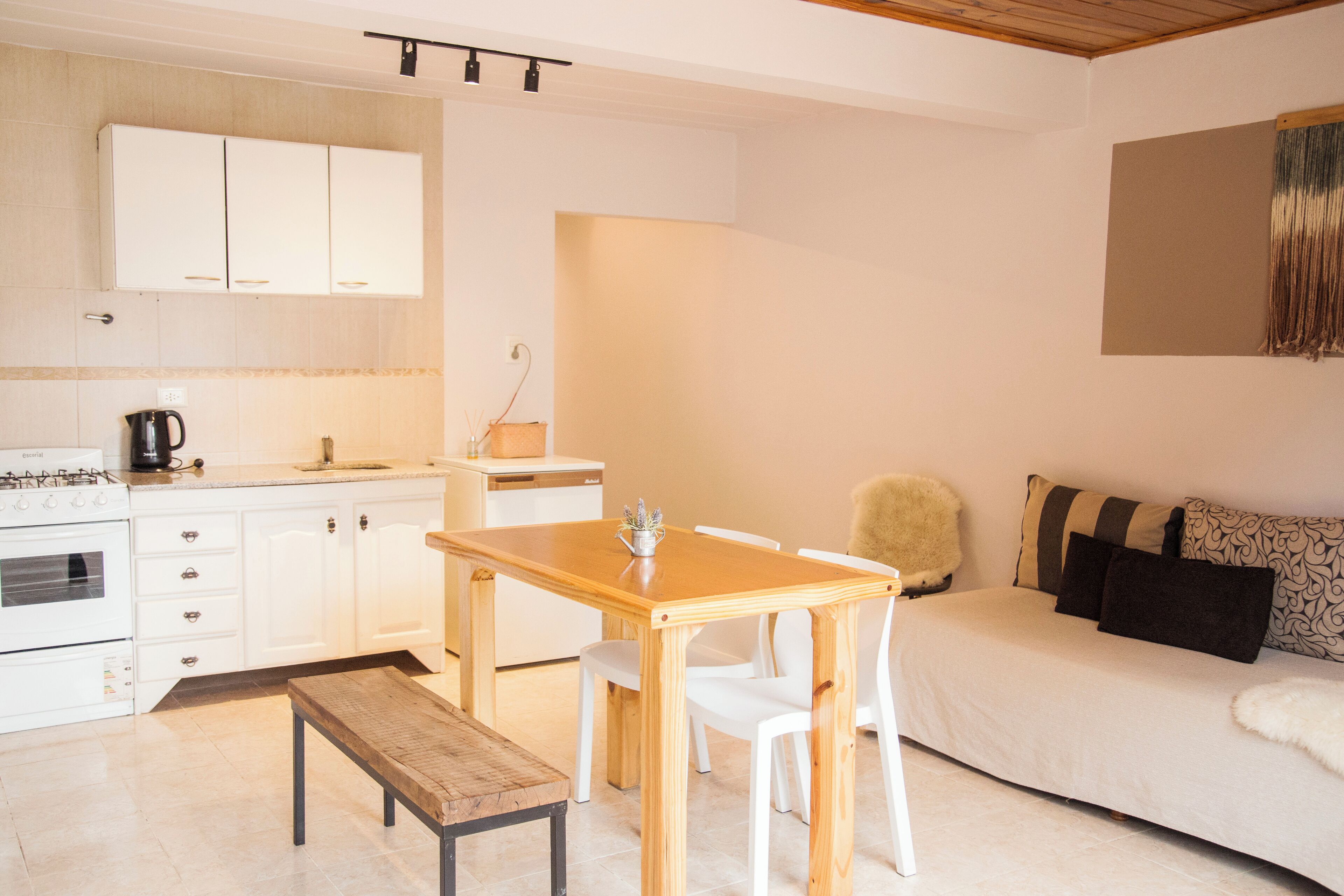 Un espace de vie compact comprenant un coin cuisine, une table à manger avec des chaises, un canapé et un banc.