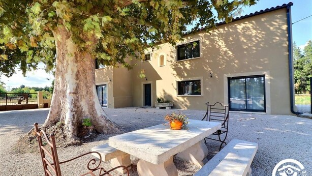 A building with a large tree in front, a patio with a table and chairs, and a gravel ground. - Gîte Spacieux, Rénové, Climatisé Avec Grande Piscine Sécurisée, Jardin Clos (Châteaurenard)