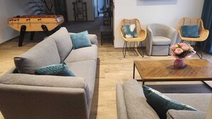 A modern living room with a sofa, two wicker chairs, a coffee table, and a TV mounted on the wall. - Gîte Spacieux, Rénové, Climatisé Avec Grande Piscine Sécurisée, Jardin Clos (Châteaurenard)