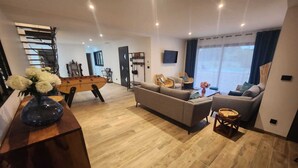 A modern living room with a sofa, a coffee table, a foosball table, and a TV. - Gîte Spacieux, Rénové, Climatisé Avec Grande Piscine Sécurisée, Jardin Clos (Châteaurenard)