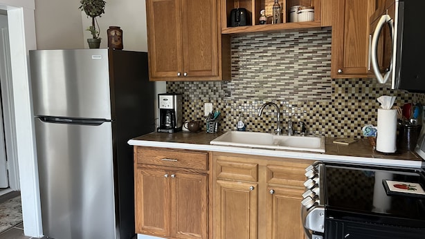 A kitchen with wooden cabinets, a stainless steel refrigerator, a coffee maker, and a microwave. - Garden House, Unit B (Hot Springs)
