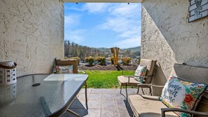 A patio with a table and two chairs, a basket, and a sign that reads "home sweet home." - 2BR w/MTN Views + Downtown Views! Community Pool - Walk to Parkway! (Gatlinburg)