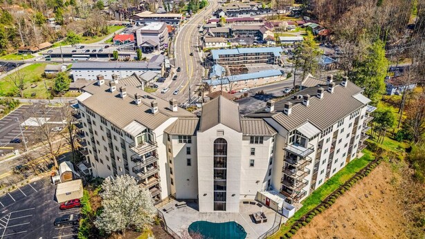 A multi-story hotel with a central courtyard and a swimming pool. - 2BR w/MTN Views + Downtown Views! Community Pool - Walk to Parkway! (Gatlinburg)