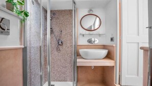 A bathroom with a glass shower enclosure, a white sink, and a mirror above it.