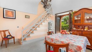 A dining area with a table set for four, a staircase, and a wooden cabinet with glass doors.