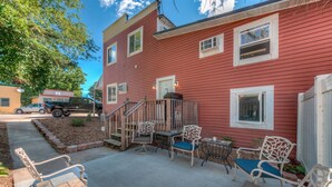 A red building with a covered patio area featuring outdoor furniture and a small table.