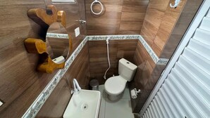 Een kleine badkamer met een houten wastafelmeubel, een wastafel, een toilet en een douchehoek.