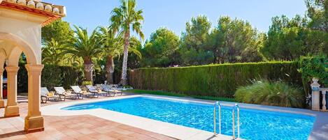 A swimming pool with lounge chairs and palm trees.
