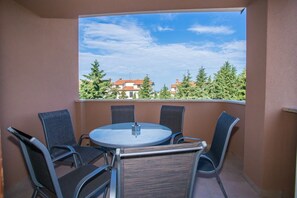 A balcony with a round table and four chairs, a clear view of buildings and trees in the background. - Three bedroom apartment Milohanic IV (Porec)