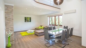 Ein modernes Wohnzimmer mit Essbereich, einer Treppe und einem großen Fenster.