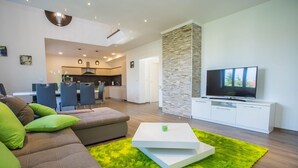 Ein modernes Wohnzimmer mit einem Ecksofa, einem Flachbildfernseher und einem leuchtend grünen Teppich.