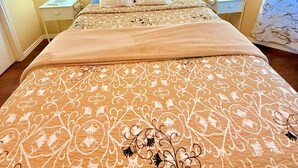 A neatly made bed with a patterned bedspread, two wall-mounted lamps, and a cityscape painting above the bed. - Sleeps8.No Stairs,Carpet-Free Near Dallas Stadiums (Arlington)