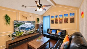 A living room with a flat-screen TV, a ceiling fan, a black leather sofa, and a wooden coffee table. - Sleeps8.No Stairs,Carpet-Free Near Dallas Stadiums (Arlington)