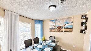 A dining room with a table set for four, a blue accent wall, and a ceiling with a textured pattern. - Sleeps8.No Stairs,Carpet-Free Near Dallas Stadiums (Arlington)