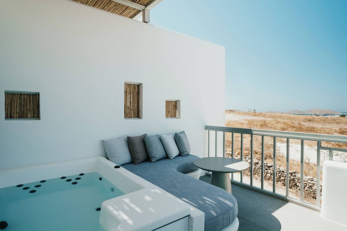 A modern outdoor seating area with a pool, a sofa with cushions, and a small table.