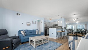 Un salon moderne avec un canapé bleu, un fauteuil en cuir noir et une table basse en bois.