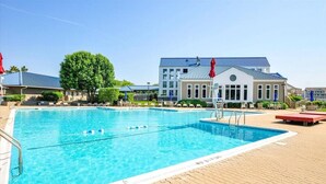 Une piscine à l’eau d’un bleu cristallin, entourée d’une terrasse dallée agrémentée de chaises longues et de parasols.