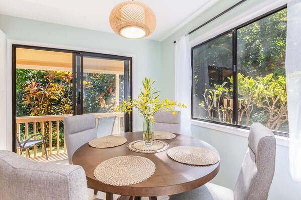 Un comedor con una mesa redonda, sillas grises y un jarrón con flores amarillas.