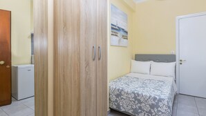A bedroom with a bed, a wardrobe, and a painting on the wall.