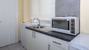 A compact kitchen with a built-in oven, a sink, and white cabinetry.