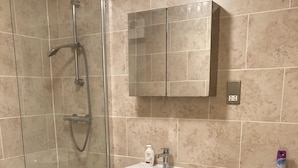 Een badkamer met een douchecabine van glas, een wastafel op een voetstuk en een toilet.