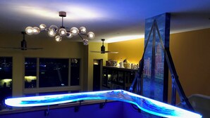 Een moderne keuken met een gebogen aanrecht, hangende verlichting en een stadsgezicht muurschildering.