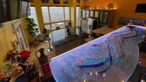 Een moderne keuken met een groot schiereiland, een eethoek en uitzicht op de stad door grote ramen.