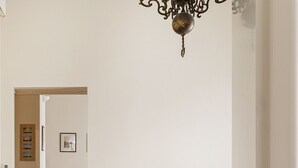 Uma sala de estar com um sofá de couro branco, um banco de madeira e um lustre.