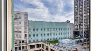 Um edifício moderno com fachada de vidro, vários andares e um terraço no telhado.