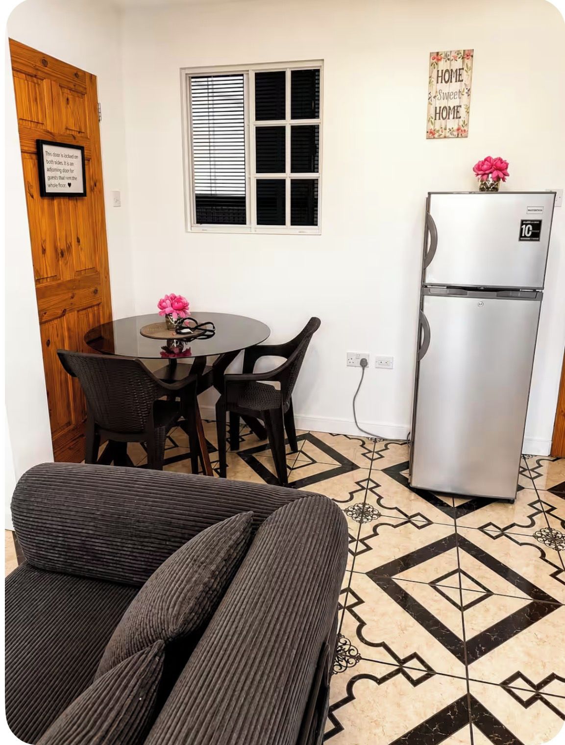 A compact room with a dining table, chairs, a refrigerator, and a sofa.