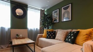 Ein Wohnzimmer mit einer Couch, einem Couchtisch, einer Heizung und einem großen Fenster mit Vorhängen.