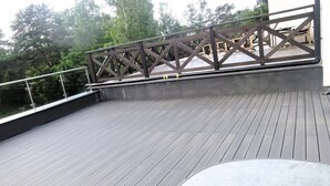 Een houten terras met een hek en uitzicht op bomen.