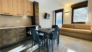 A compact kitchen with a dining area, a sofa, and a TV. - Residence VILLA LINDA (Bardonecchia)
