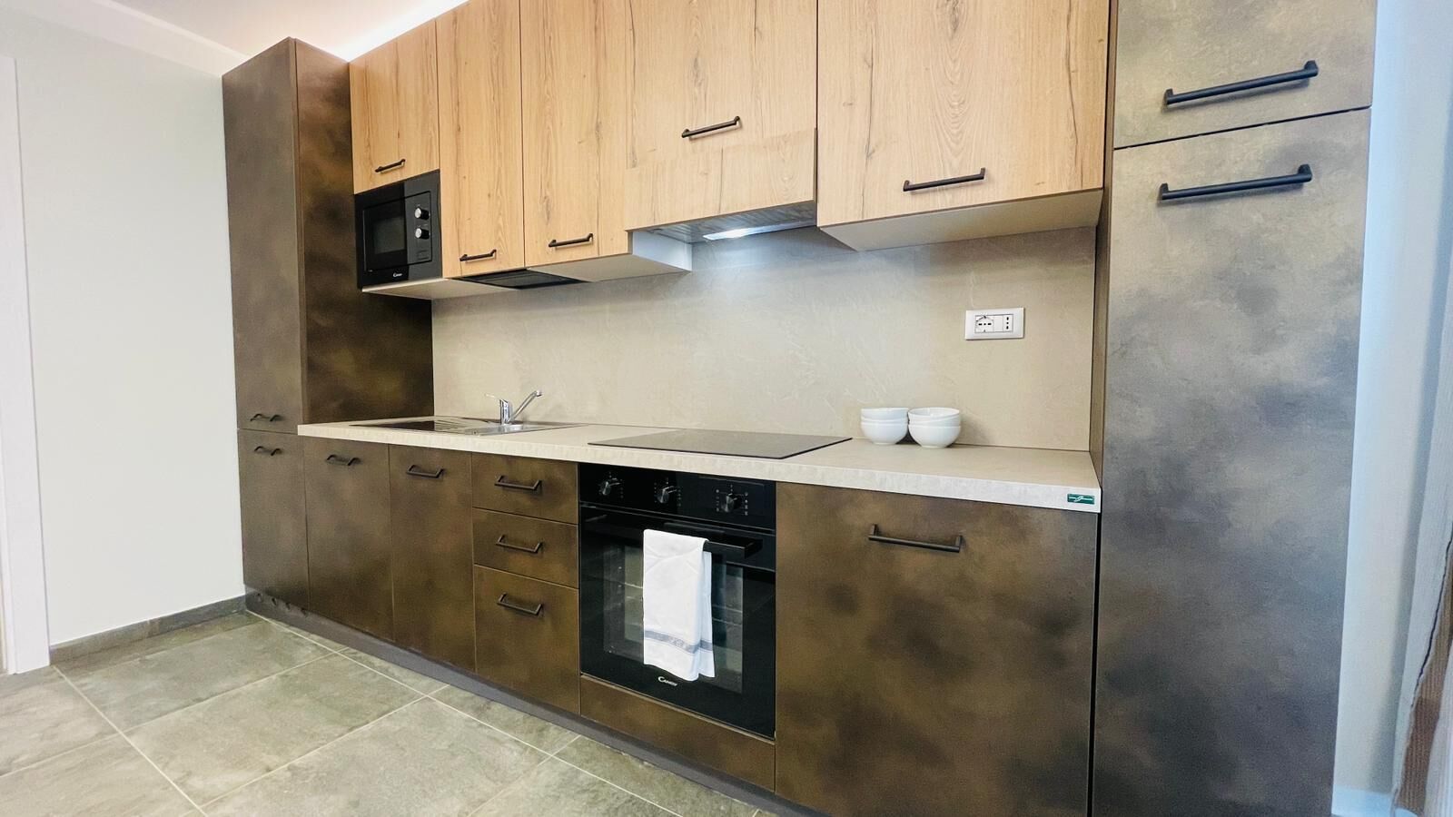 A kitchen with wooden cabinets, a built-in oven, and a microwave.