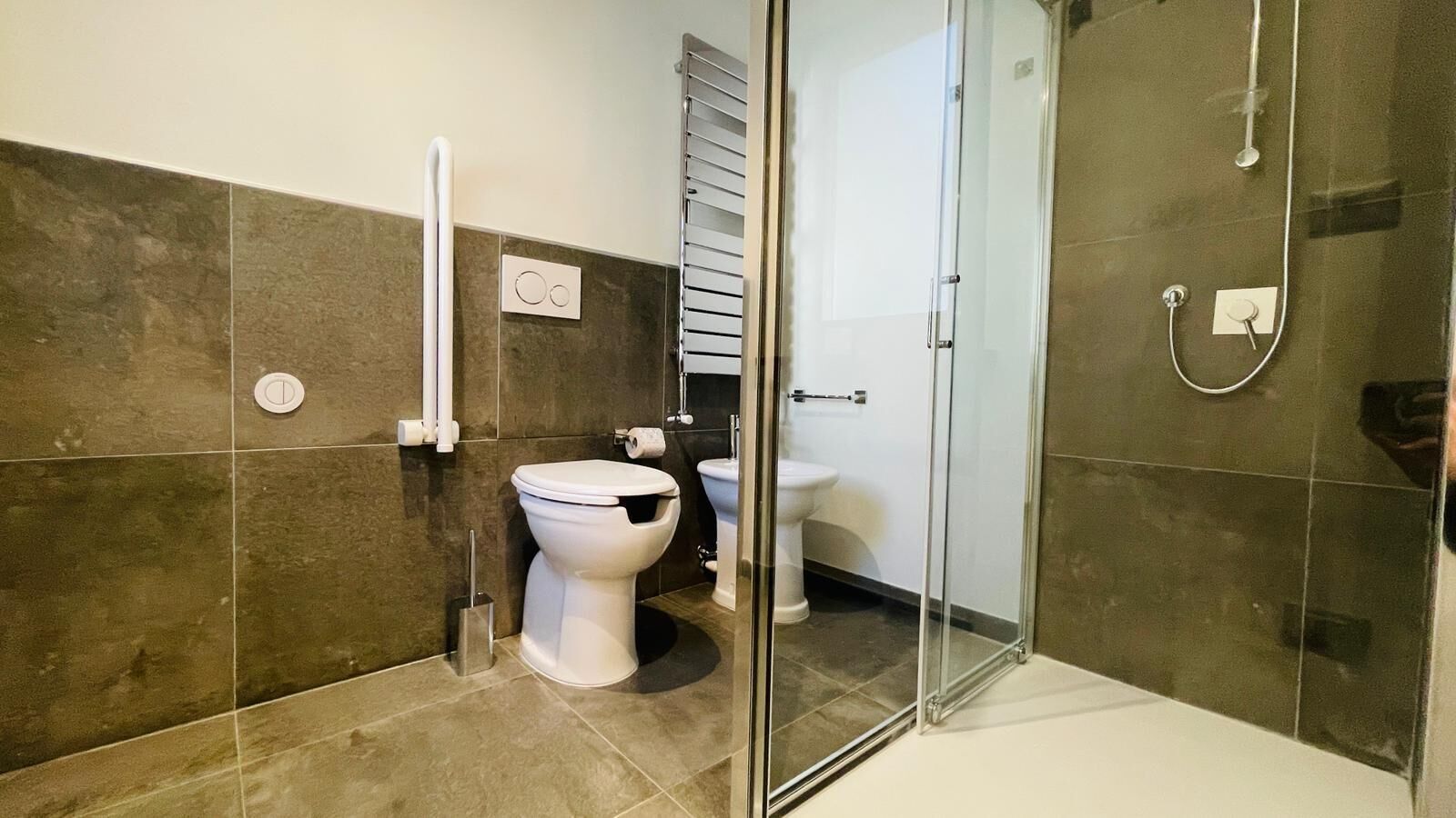 Ein modernes Badezimmer mit Toilette, Bidet und Duschkabine aus Glas.