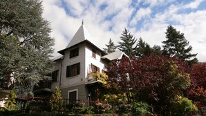 A two-story house with a steeply pitched roof, a visible chimney, and a balcony. - Residence VILLA LINDA (Bardonecchia)