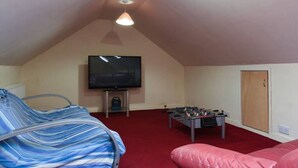 A room with a TV, a foosball table, a bed, and a door. - The Nest | Large Family Home! (Cowplain)